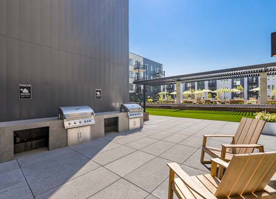 A patio with wooden chairs and a grill.
