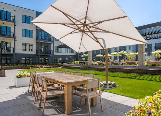 A patio with a table and chairs under a large umbrella.