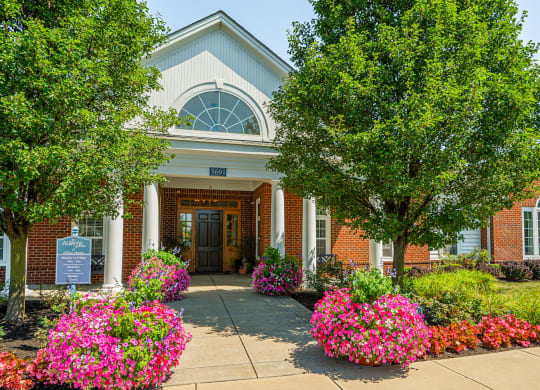 the front of a brick building with flowers and trees