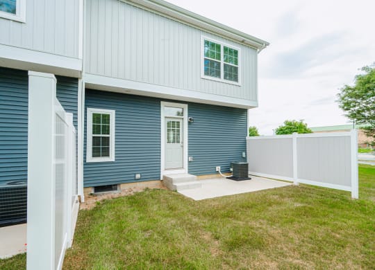 the front door of a blue house with a white fence