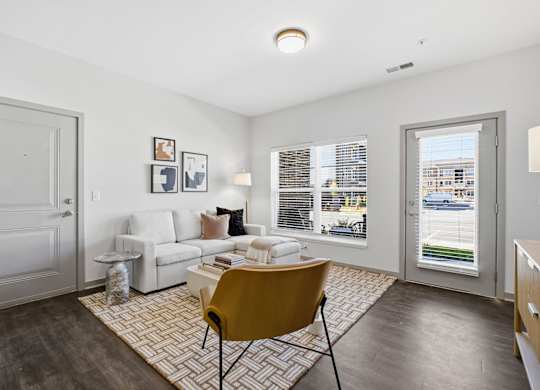 A living room with a yellow chair and a white sofa.