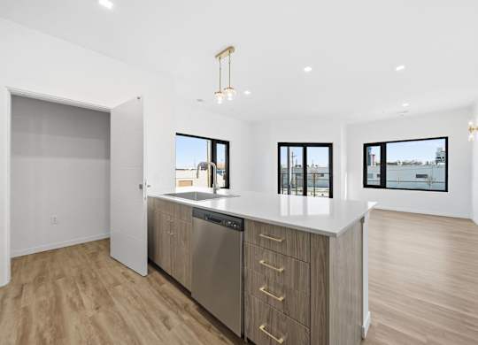 A modern kitchen with wooden floors and stainless steel appliances.