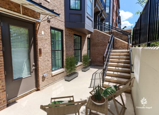 a patio with chairs and a table on the side of a building