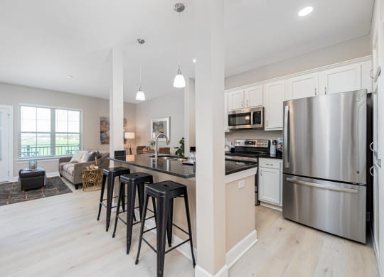 an open kitchen and living room with stainless steel appliances and bar stools
