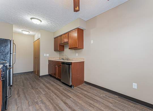 A kitchen area with wooden floors and brown cabinets