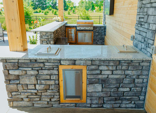 a stone bar with a grill on the side of a house