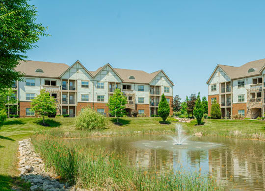 a pond with a fountain in front of an apartment building