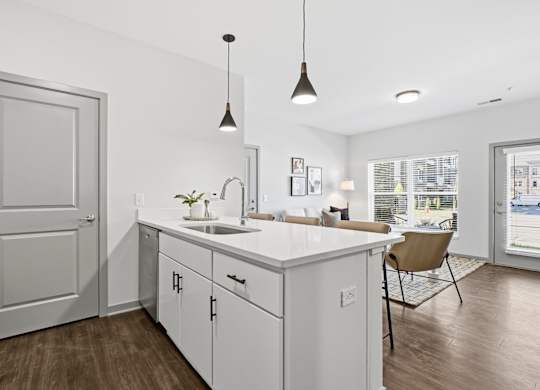 A kitchen with white cabinets and a wooden floor.
