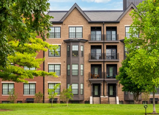 a brick apartment building with balconies and trees in front of it