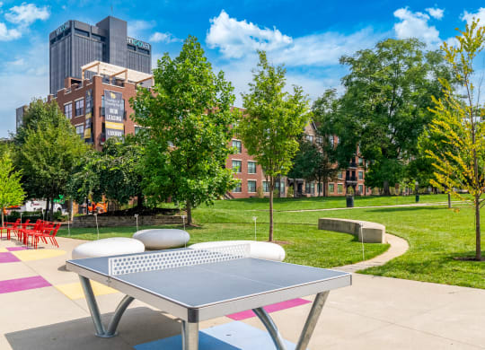a ping pong table in a park with trees and buildings in the background