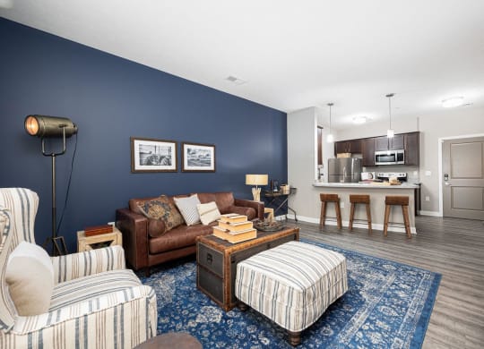 a living room with a couch and a chair in front of a kitchen