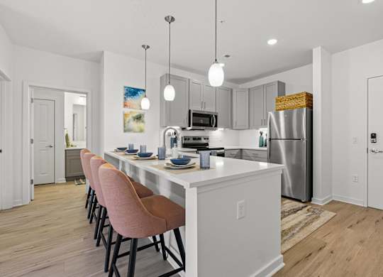 A kitchen with a white island and pink chairs.