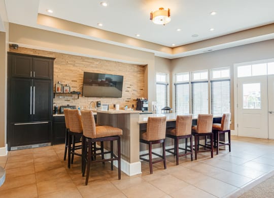 a kitchen with a bar with chairs and a television