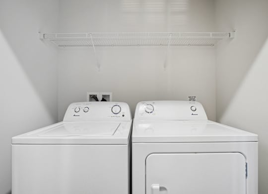 Two white washing machines in a small laundry room.