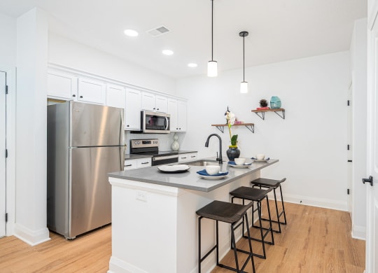 a kitchen with a large island and stainless steel refrigerator