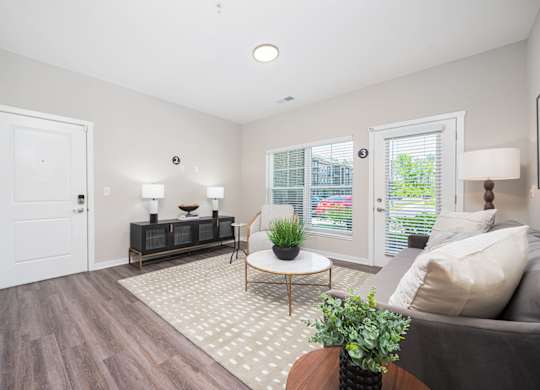 A living room with a grey couch, a wooden coffee table, and a white door.