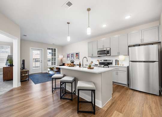 A modern kitchen with a bar stool and a refrigerator.