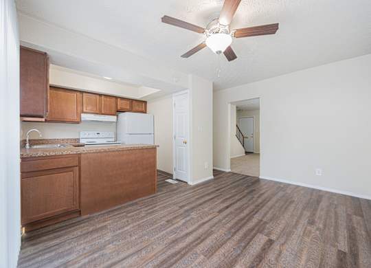 A room with a brown floor and a ceiling fan.