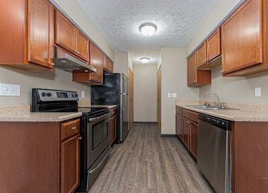 A kitchen with brown cabinets and black appliances.
