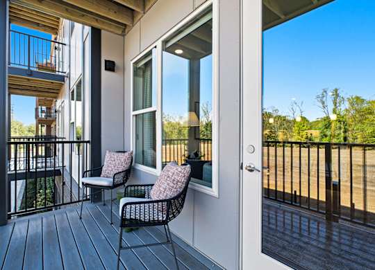 A balcony with a chair and a table with a cushion on it.