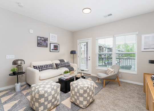 A living room with a couch, ottoman, and a chair.