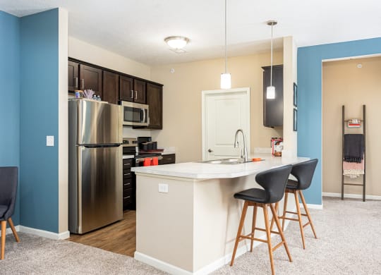 a kitchen with a island and a stainless steel refrigerator