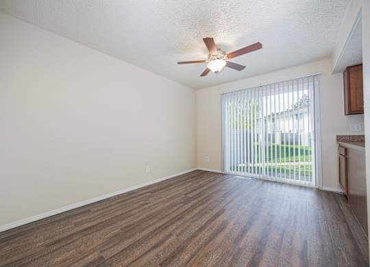 A room with a ceiling fan and sliding glass doors.
