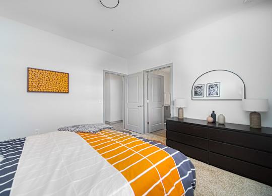 A bedroom with a bed, dresser, and two framed pictures on the wall.