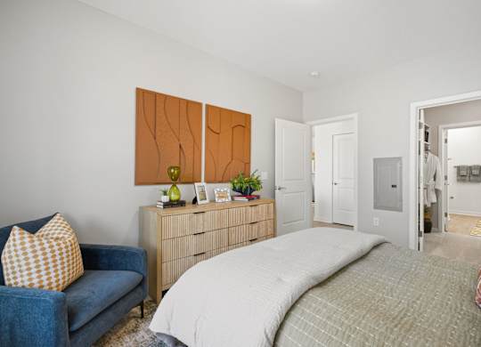 A bedroom with a bed, a couch, and a dresser.