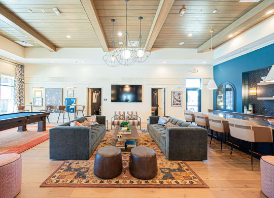 a living room with couches and chairs and a pool table
