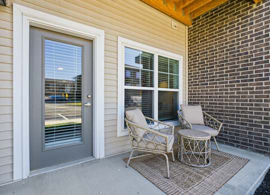 A patio with a chair and table outside a house.