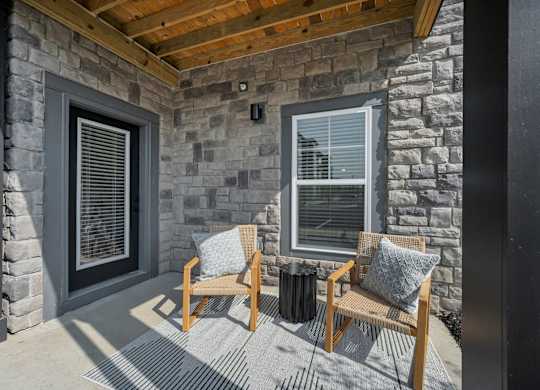 A patio with a wooden bench and a stone wall.