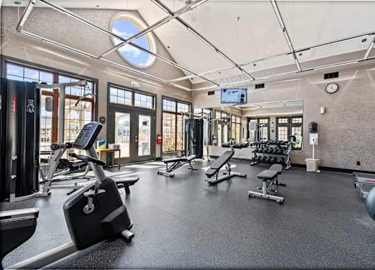 A gym with a variety of equipment including treadmills, weights, and exercise machines.