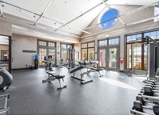 A gym with a variety of equipment including treadmills, weights, and exercise machines.