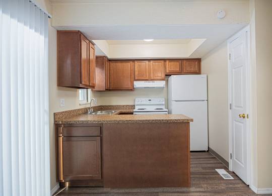 A kitchen with brown cabinets and a white refrigerator.