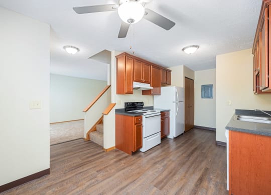 an empty kitchen with a ceiling fan and a staircase