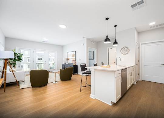 A modern kitchen with white cabinets and a wooden floor.