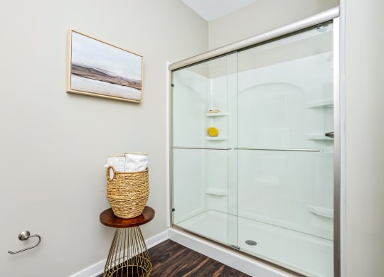 a bathroom with a glass shower and a basket next to it
