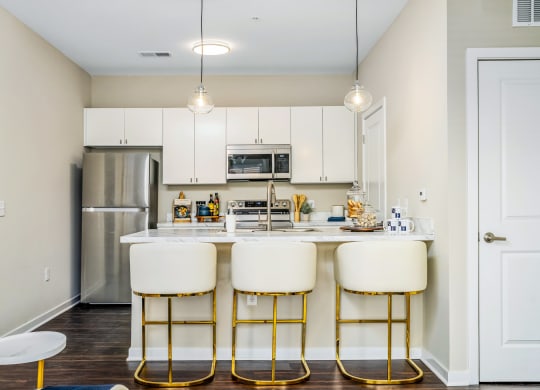 a kitchen with white cabinets and a bar with three stools