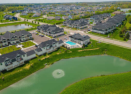A bird's eye view of a residential area with houses and a pond.