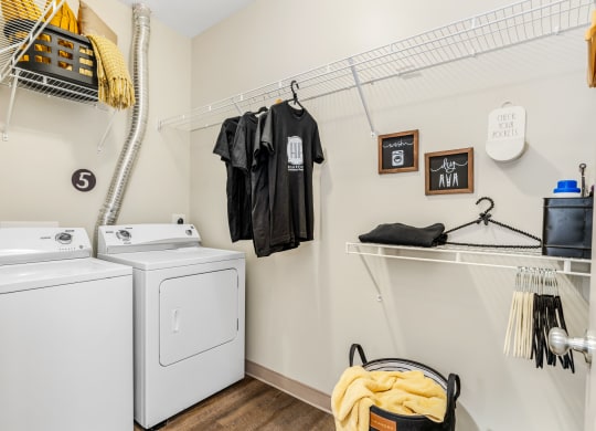a washer and dryer in a laundry room with clothes hanging on the wall