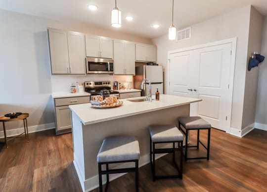 a kitchen with white cabinets and a large island with two stools in front of it