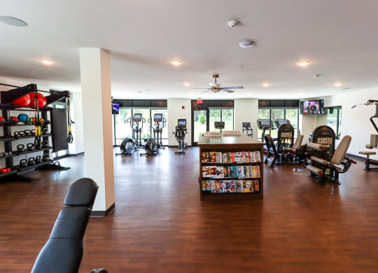 a room with a lot of exercise equipment and a bookcase full of dvds