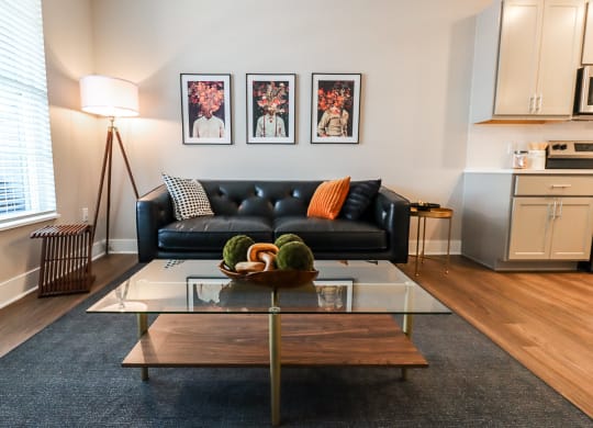 a living room with a black couch and a glass coffee table