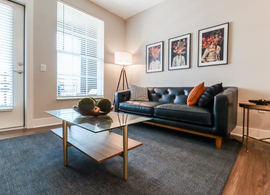 a living room with a black leather couch and a glass coffee table