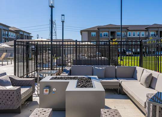 A black metal fence surrounds a concrete patio with a bench and a table.