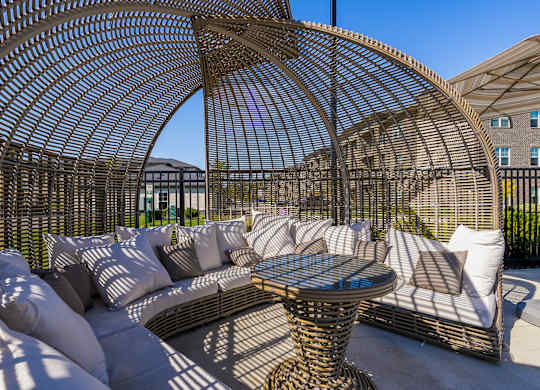 A patio with a wicker table and chairs under a canopy.