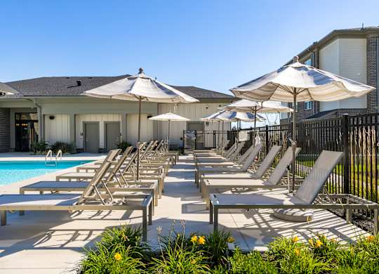 A poolside area with sun loungers and umbrellas.
