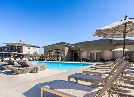 A sunny day at the pool with lounge chairs and umbrellas.
