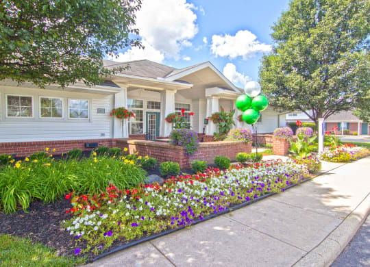the front yard of a house with flowers and a sidewalk